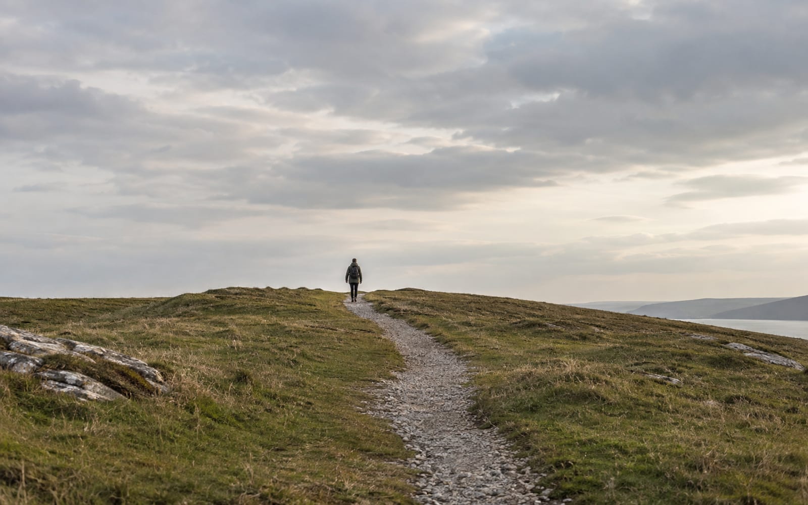 A narrow gravel path winds through grass over a low rise.