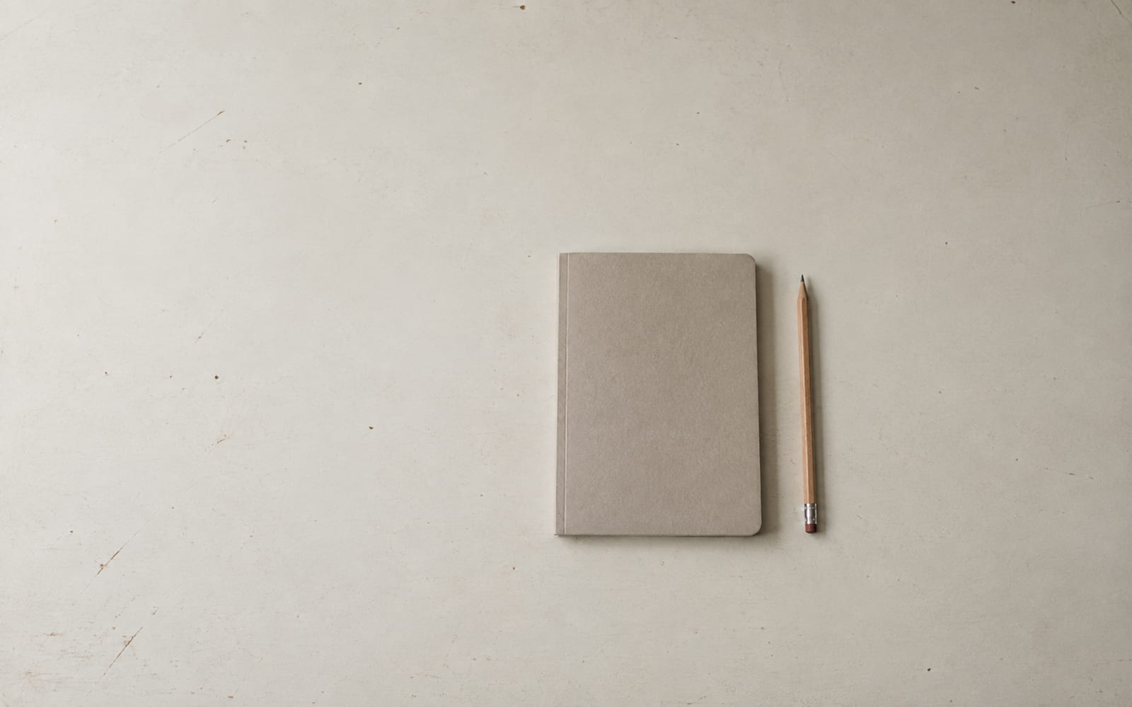 A plain notebook and pencil lie on an otherwise empty desk.